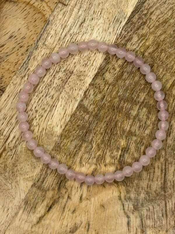 Pulsera de cuarzo rosa sobre base de madera